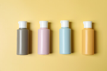 Cosmetic travel kit. Small containers of personal care products on yellow background, flat lay
