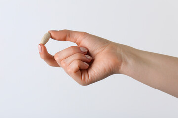 Woman holding vitamin pill on white background, closeup. Health supplement