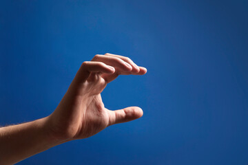 Man holding something in hand on blue background, closeup. Space for text