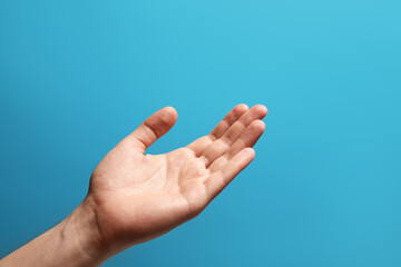 Man holding something in hand on light blue background, closeup