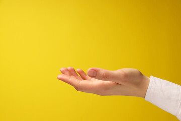 Woman holding something in hand on yellow background, closeup. Space for text