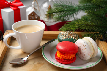 Different decorated Christmas macarons served with coffee on table