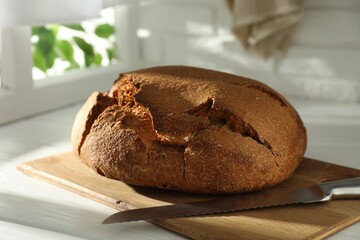 Freshly baked sourdough bread on white wooden table indoors
