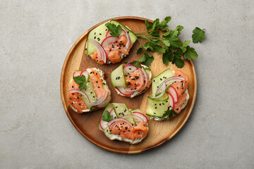 Tasty canapes with salmon served on light grey table, top view
