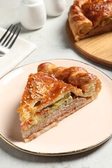 Piece of tasty homemade pie with filling on light grey table