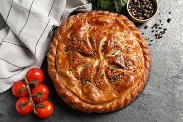 Tasty homemade pie, spices and fresh tomatoes on grey table, flat lay