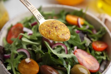 Spoon with tasty vinegar based sauce (Vinaigrette) over salad, closeup
