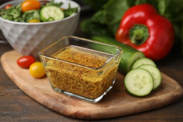 Tasty vinegar based sauce (Vinaigrette) in bowl and products on wooden table, closeup