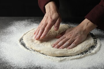 Woman kneading pizza dough at table, closeup