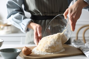 Woman kneading dough at white wooden table in kitchen, closeup