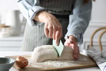 Woman cutting dough at white wooden table in kitchen, closeup - Powered by Adobe