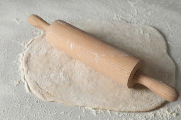 Raw dough and rolling pin on table