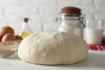 Raw dough and ingredients on white table