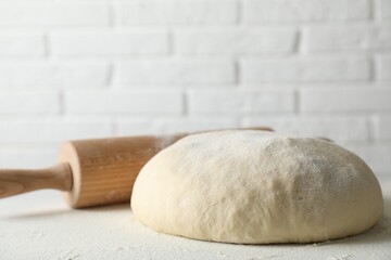 Raw dough and rolling pin on table