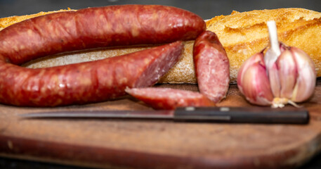 Rustic bread with salami and garlic on wooden board