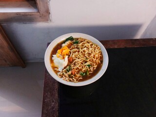Boiled instant noodles topped with egg and vegetables on the table. fast food. delicious noodle soup
