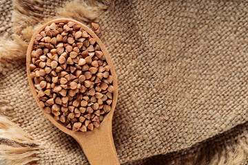 Dry Buckwheat in Wooden Spoon on Burlap, Copy Space
