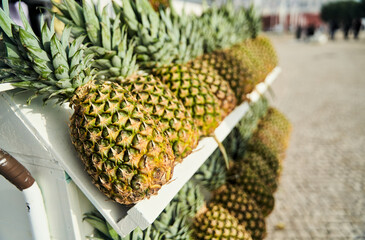 A cart filled with pineapples, a type of terrestrial plant and fruit, on a cobblestone street. The...