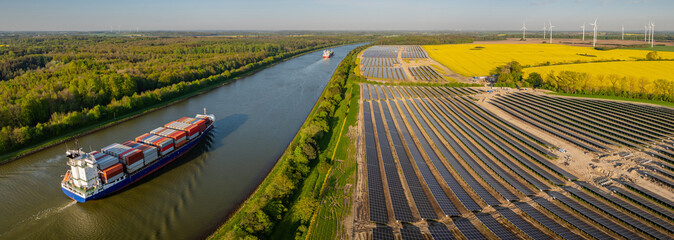 Ground-mounted solar photovoltaic panels near canal, where ships gracefully navigates waterway....