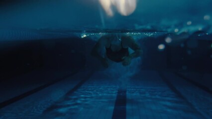 Woman swimming butterfly stroke in a pool from above and below the water