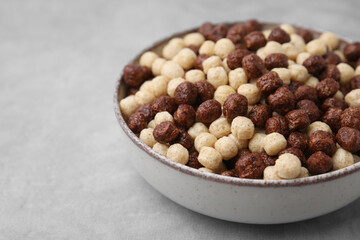 Tasty cereal balls in bowl on grey table, closeup. Space for text