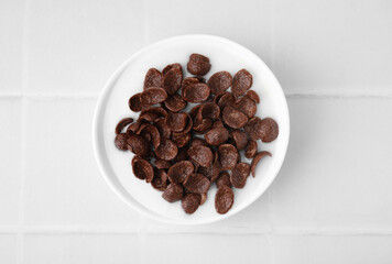 Breakfast cereal. Chocolate corn flakes and milk in bowl on white tiled table, top view