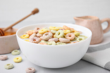 Cereal rings and milk in bowl on white table, closeup