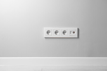 Electric power sockets on light grey wall indoors