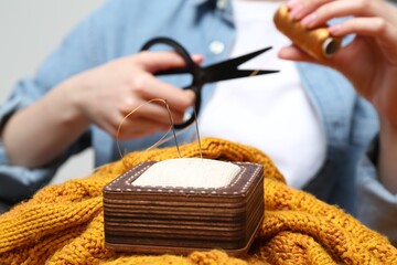 Woman sewing sweater, focus on pin cushion