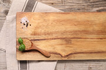 Cutting board and spices on wooden table, top view. Space for text