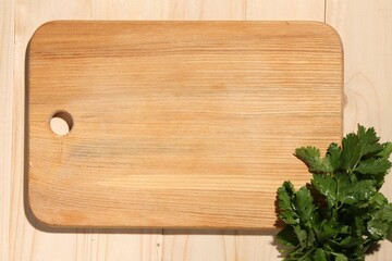Cutting board and parsley on wooden table, flat lay. Space for text