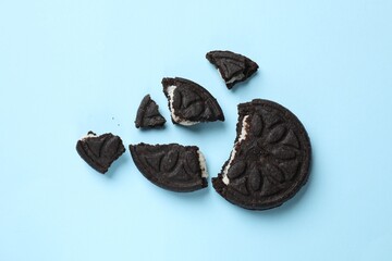 Naklejka premium Pieces of tasty sweet sandwich cookies on light blue background, flat lay