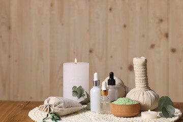 Different aromatherapy products, burning candles and eucalyptus leaves on wooden table, space for text