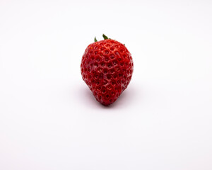 a very small strawberry on a white tablecloth with a leaf