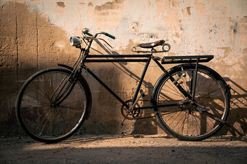 Vintage old bicycle leaning against dirty old wall background. Classic bike on decay wall with...