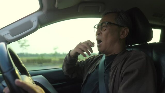 Young Senior old man driver was drowsy. Grandfather he yawned and was about to fall asleep. doze off Driving for a long time, sleep deprivation. Aging Society concept.