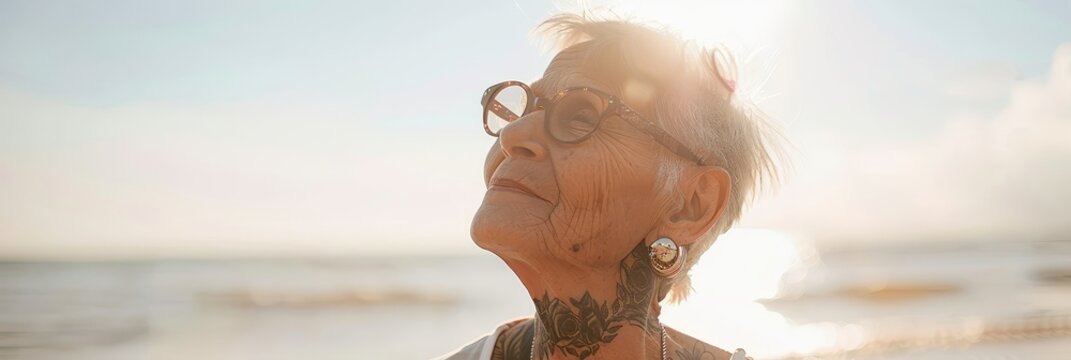 Aged to Perfection: Confident Senior Flaunts Intricate Tattoos Under the Warm Sun, Embracing the Beach Day with Unabated Zeal