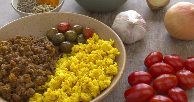 Homemade naurangi (ricebean) dal served with pickled chilies and millet groats cooked with turmeric.  Raw ricebean, spices and other ingredients on the side.  Table spin.