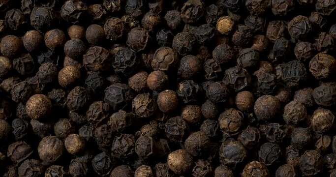Whole black pepper rotating in a circle as an abstract food texture.  Rotation around the center point.