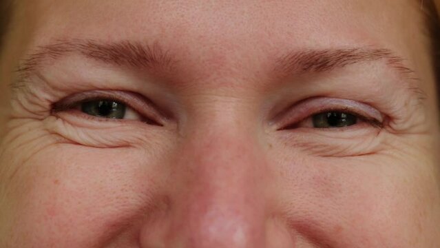 Close-up shot of adult caucasian woman's eyes as she looks to camera and smiles. Stare life right in the eyes, accept your age.