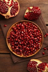 Ripe juicy pomegranates and grains on wooden table, flat lay