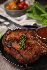 Tasty grilled meat, rosemary and marinade on brown textured table, closeup