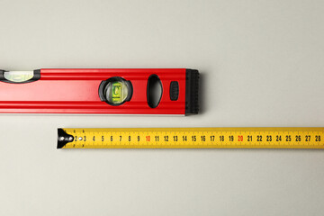 Building level and tape measure on beige background, top view