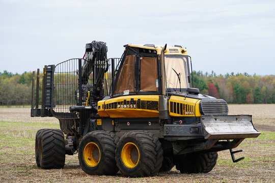 Ponsse Buffalo tree timber hauler sits next to a forest on a farm field.