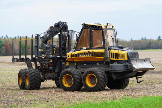 Ponsse Buffalo tree timber hauler sits next to a forest on a farm field.