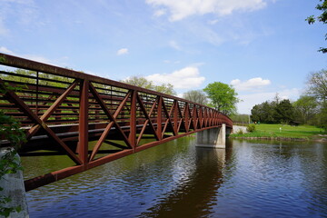 An iron steel walking path bridge stretches across a river. 