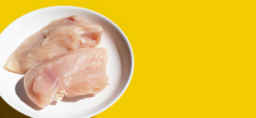 Uncooked raw chicken  breast fillets on yellow background.