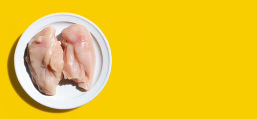 Uncooked raw chicken  breast fillets on yellow background.