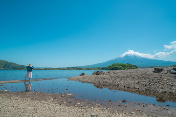 富士山と河口湖が見えるところを歩く女性