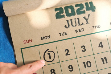 Hand pointing on July 1 2024 date on calendar flat lay in blue background. Canada day celebration...